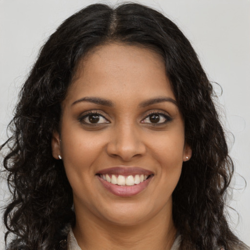 Joyful black young-adult female with long  brown hair and brown eyes