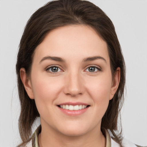 Joyful white young-adult female with medium  brown hair and grey eyes