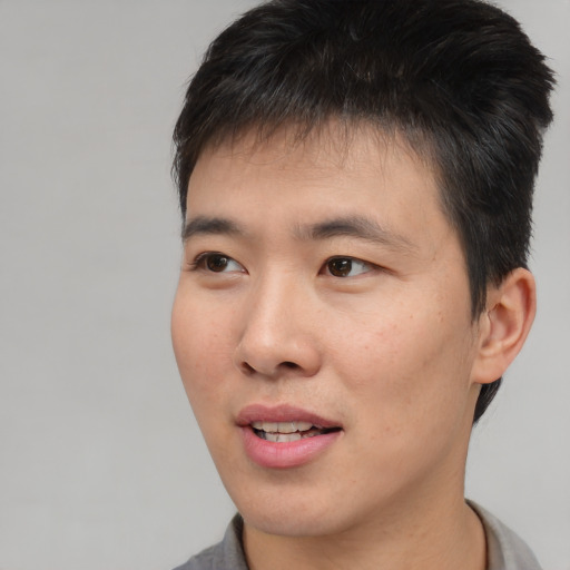 Joyful asian young-adult male with short  brown hair and brown eyes