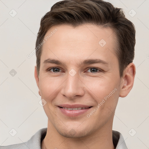 Joyful white young-adult male with short  brown hair and grey eyes