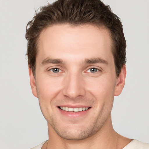 Joyful white young-adult male with short  brown hair and grey eyes