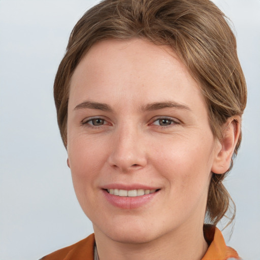 Joyful white young-adult female with medium  brown hair and grey eyes