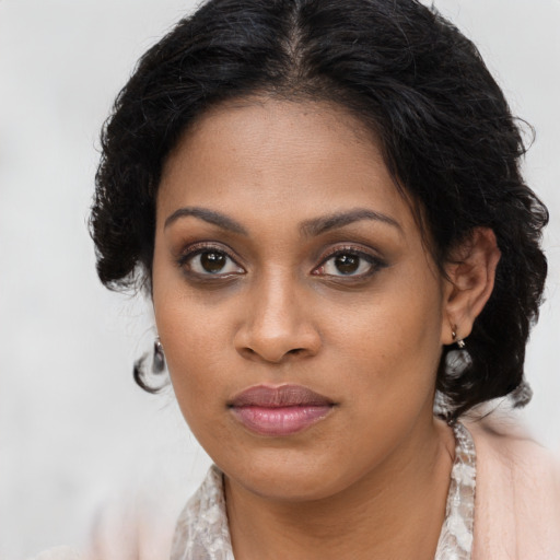 Joyful black young-adult female with long  brown hair and brown eyes