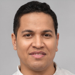 Joyful latino young-adult male with short  brown hair and brown eyes