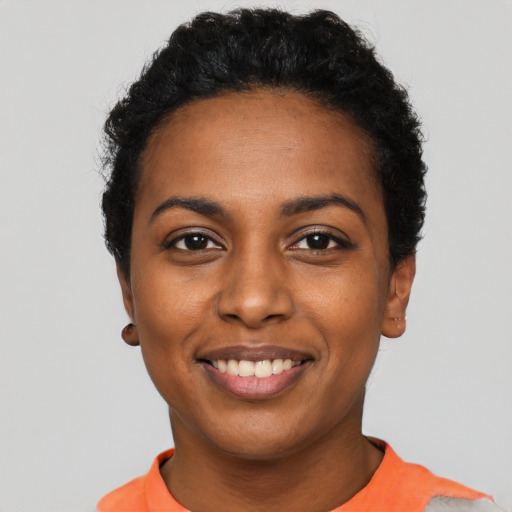 Joyful black young-adult female with short  black hair and brown eyes