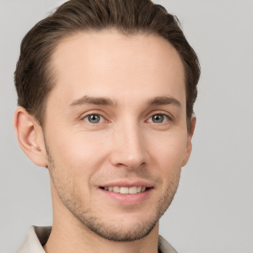 Joyful white young-adult male with short  brown hair and grey eyes