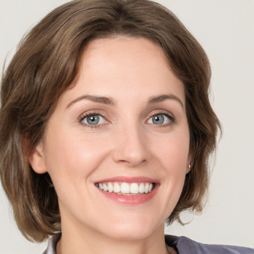 Joyful white young-adult female with medium  brown hair and grey eyes