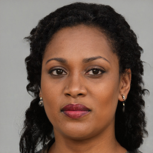 Joyful black young-adult female with long  brown hair and brown eyes