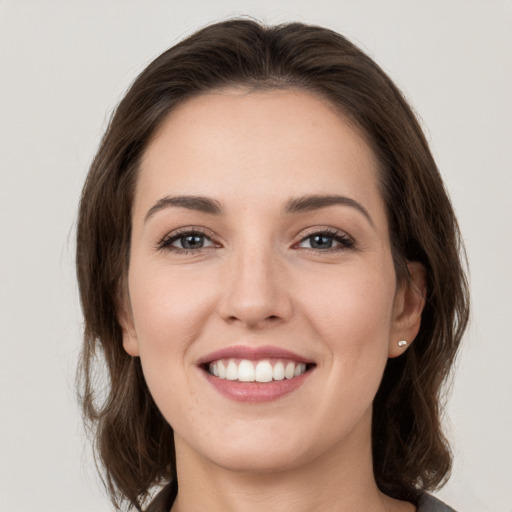 Joyful white young-adult female with medium  brown hair and grey eyes