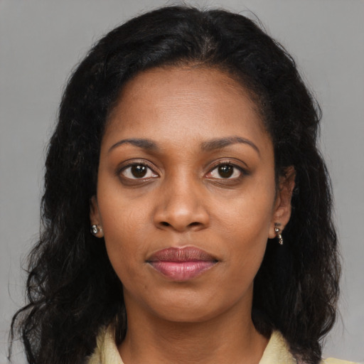 Joyful black young-adult female with long  brown hair and brown eyes