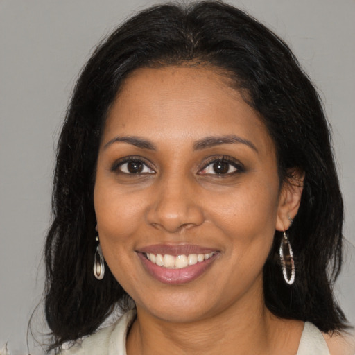 Joyful black young-adult female with long  brown hair and brown eyes