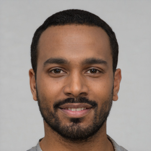 Joyful black young-adult male with short  black hair and brown eyes