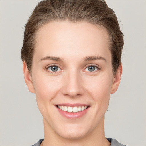 Joyful white young-adult female with short  brown hair and grey eyes