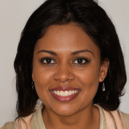 Joyful black young-adult female with long  brown hair and brown eyes