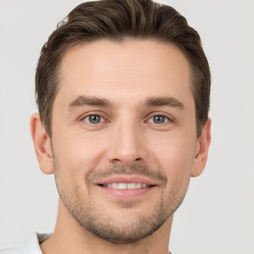 Joyful white young-adult male with short  brown hair and grey eyes