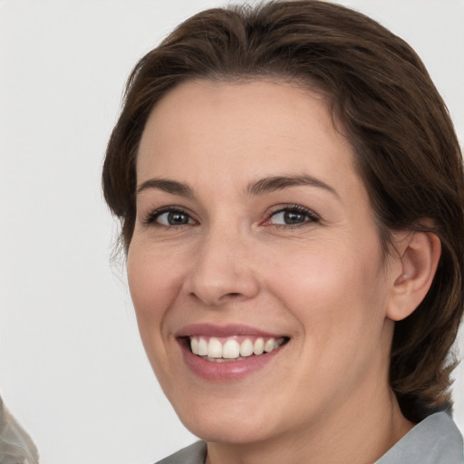 Joyful white young-adult female with medium  brown hair and grey eyes