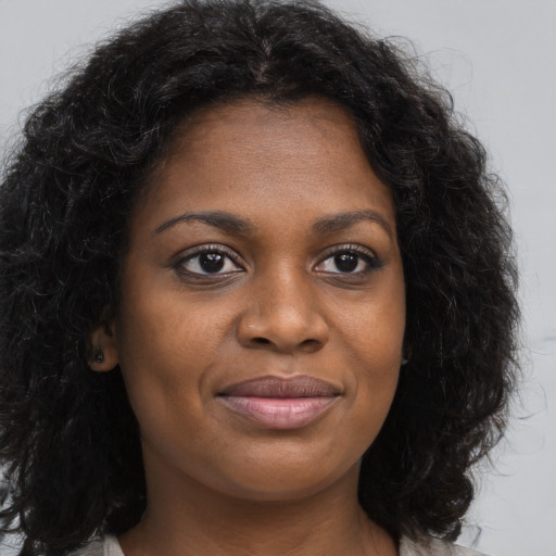 Joyful black young-adult female with long  brown hair and brown eyes