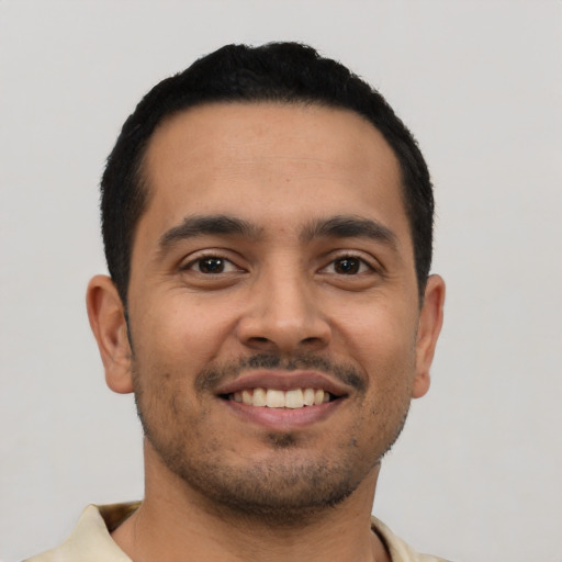 Joyful latino young-adult male with short  black hair and brown eyes