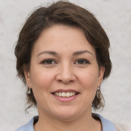 Joyful white young-adult female with medium  brown hair and grey eyes