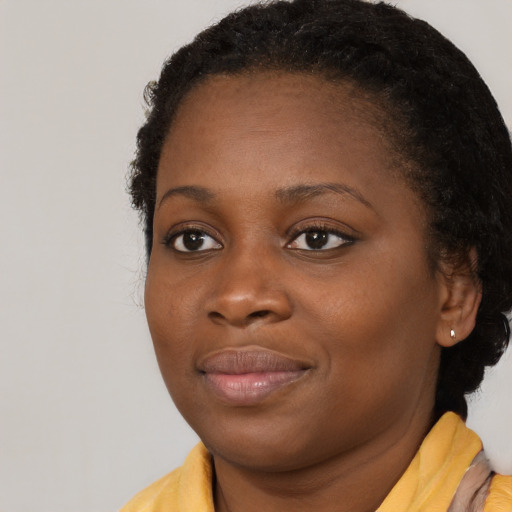 Joyful black young-adult female with long  brown hair and brown eyes