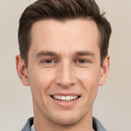 Joyful white young-adult male with short  brown hair and grey eyes