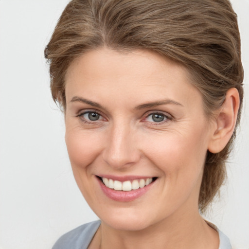 Joyful white young-adult female with medium  brown hair and grey eyes