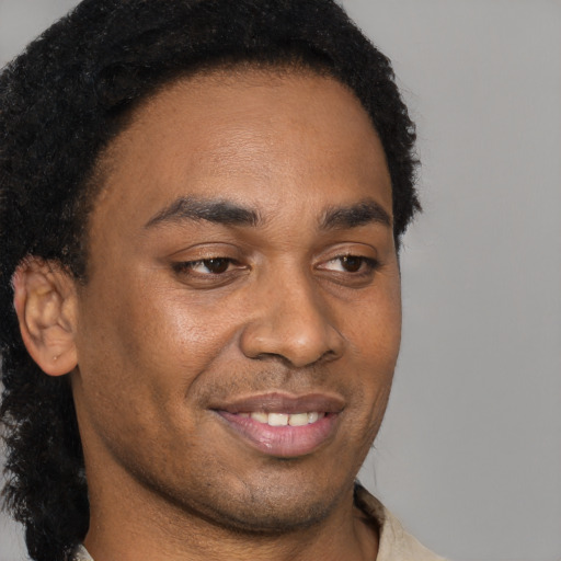 Joyful black young-adult male with short  brown hair and brown eyes