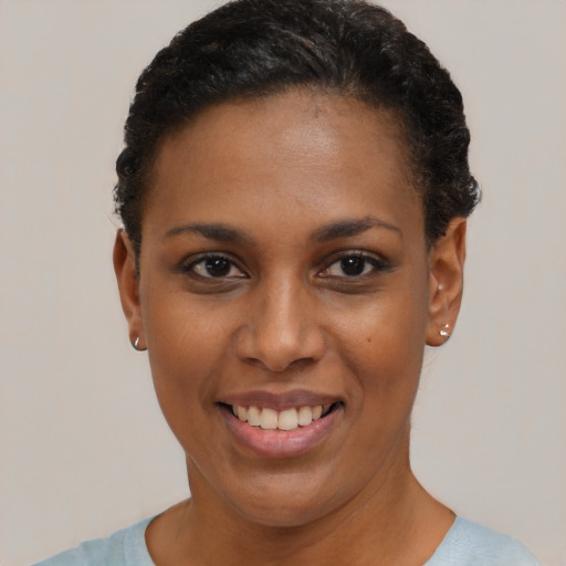 Joyful black young-adult female with short  black hair and brown eyes