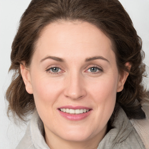 Joyful white young-adult female with medium  brown hair and grey eyes