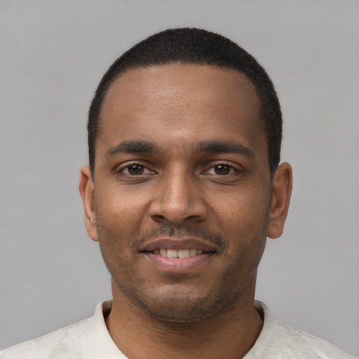 Joyful black young-adult male with short  black hair and brown eyes