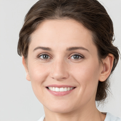 Joyful white young-adult female with medium  brown hair and grey eyes