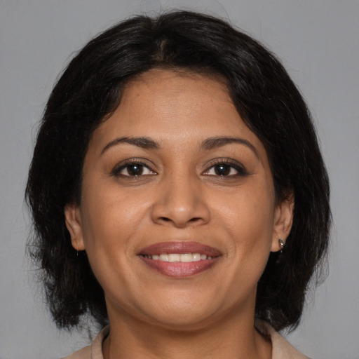 Joyful latino adult female with medium  brown hair and brown eyes