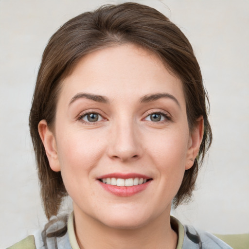 Joyful white young-adult female with medium  brown hair and grey eyes