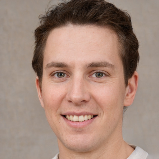 Joyful white young-adult male with short  brown hair and grey eyes