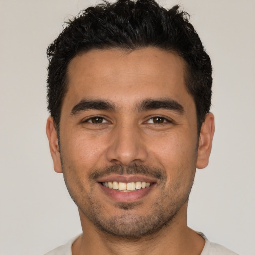 Joyful latino young-adult male with short  brown hair and brown eyes