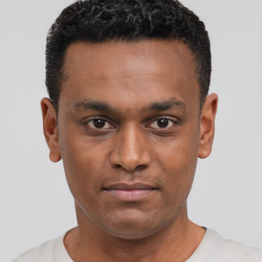 Joyful black young-adult male with short  brown hair and brown eyes