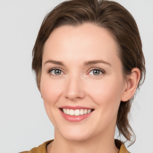 Joyful white young-adult female with medium  brown hair and grey eyes