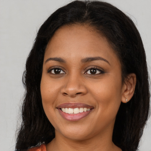 Joyful black young-adult female with long  brown hair and brown eyes