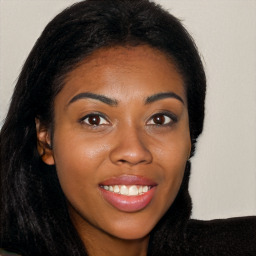 Joyful black young-adult female with long  brown hair and brown eyes