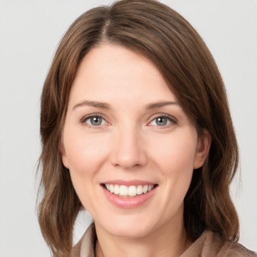 Joyful white young-adult female with medium  brown hair and grey eyes