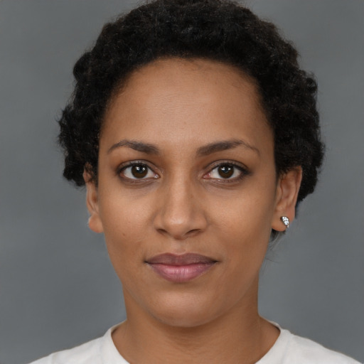 Joyful black young-adult female with short  black hair and brown eyes