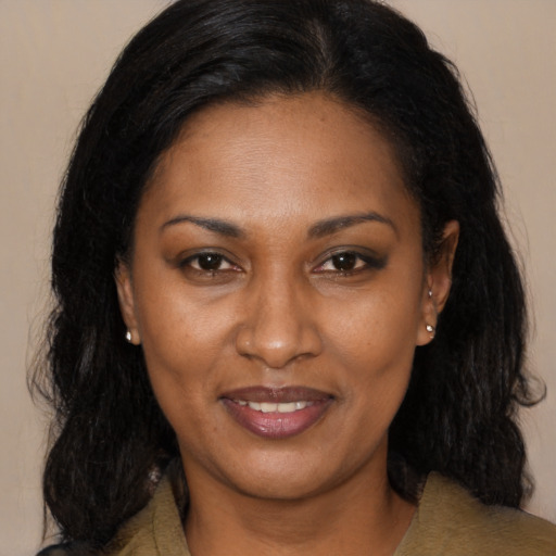 Joyful black adult female with long  brown hair and brown eyes