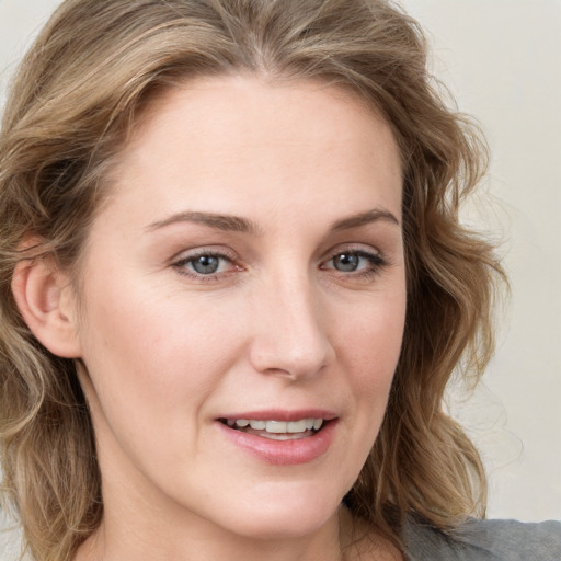 Joyful white young-adult female with long  brown hair and blue eyes