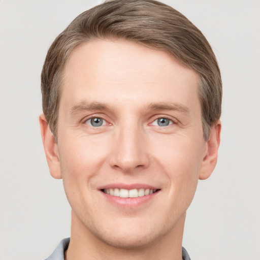 Joyful white young-adult male with short  brown hair and grey eyes