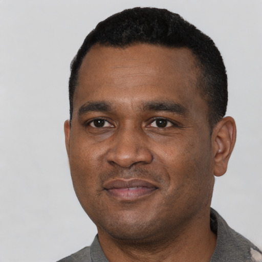 Joyful black young-adult male with short  black hair and brown eyes