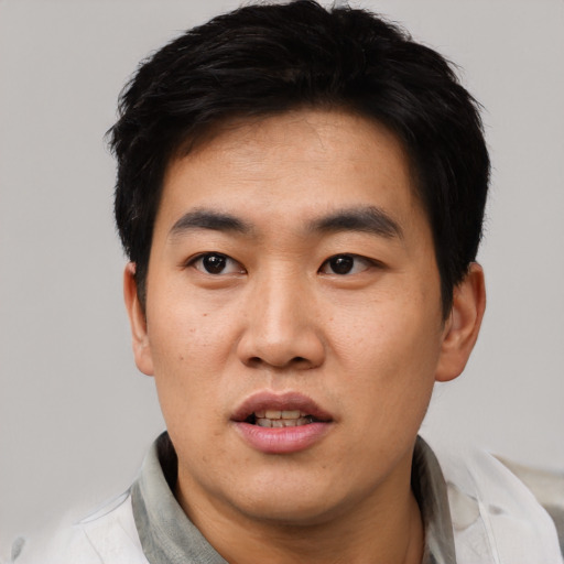 Joyful asian young-adult male with short  black hair and brown eyes