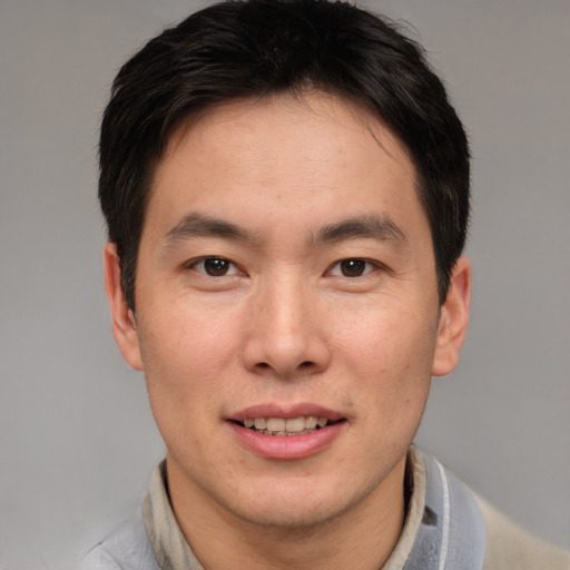 Joyful asian young-adult male with short  brown hair and brown eyes