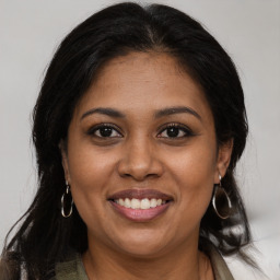 Joyful black young-adult female with long  brown hair and brown eyes