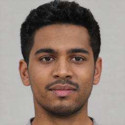 Joyful latino young-adult male with short  black hair and brown eyes