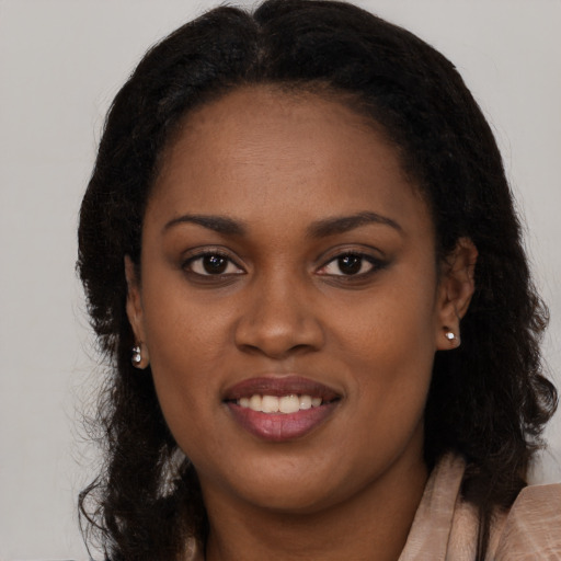 Joyful black young-adult female with long  brown hair and brown eyes